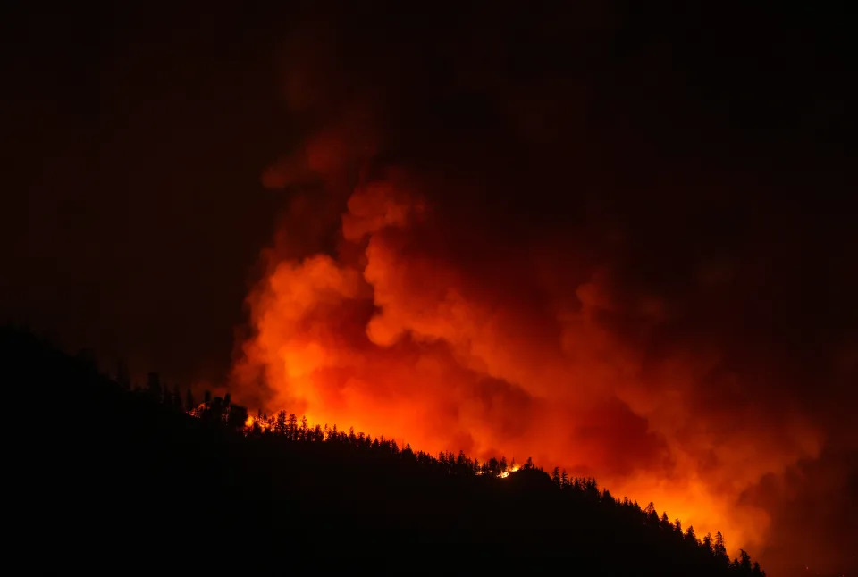 The McDougall Creek wildfire burns on the mountainside above houses in West Kelowna, B.C., on Friday, August 18, 2023. THE CANADIAN PRESS/Darryl Dyck