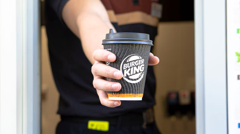 worker holding Burger King coffee cup