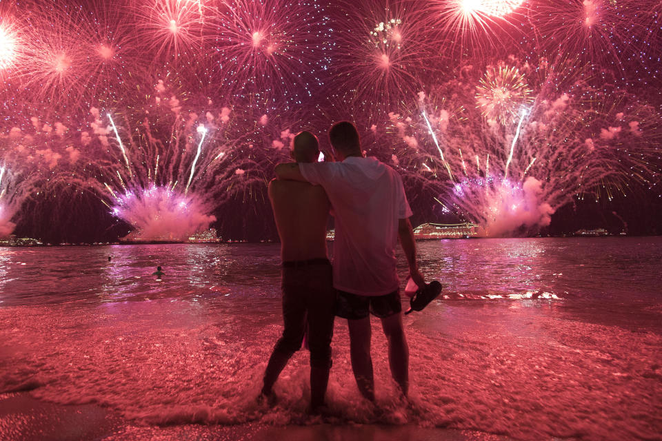 Two men watch the fireworks exploding over Copacabana Beach during the New Year's celebrations in Rio de Janeiro, Brazil, Tuesday, Jan. 1, 2019. (AP Photo/Leo Correa)