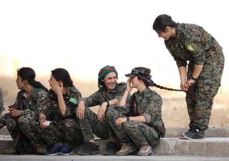 Syrian Democratic Forces (SDF) female fighters sit together on a curb in the city of Hasaka, northeastern Syria, August 9, 2017. REUTERS/Rodi Said