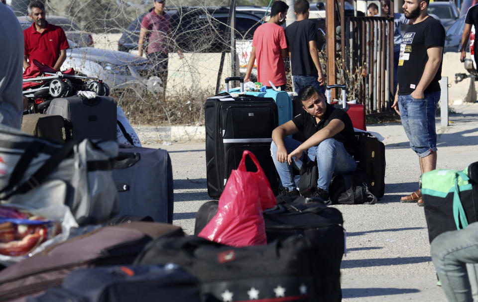 Pasajeros están sentados junto a su equipaje mientras esperan cruzar la frontera al lado egipcio del cruce Rafá, en la Franja de Gaza, el martes 11 de agosto de 2020. (AP Foto/Adel Hana)