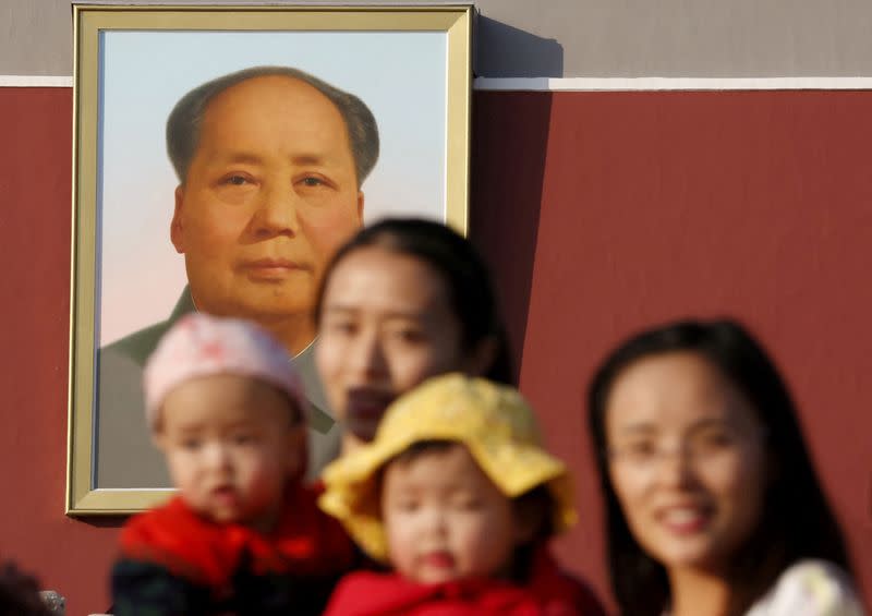 FILE PHOTO: Two women and their babies pose for photographs in front of the giant portrait of late Chinese chairman Mao Zedong on the Tiananmen Gate in Beijing