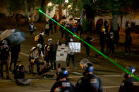 Police and protesters clash during a demonstration, early Thursday, Aug. 13, 2020, in downtown Portland. Protests have been held nightly in the city since the police killing of George Floyd in May, who died after a white officer pressed a knee to his neck in Minneapolis. (Sean Meagher/The Oregonian via AP)