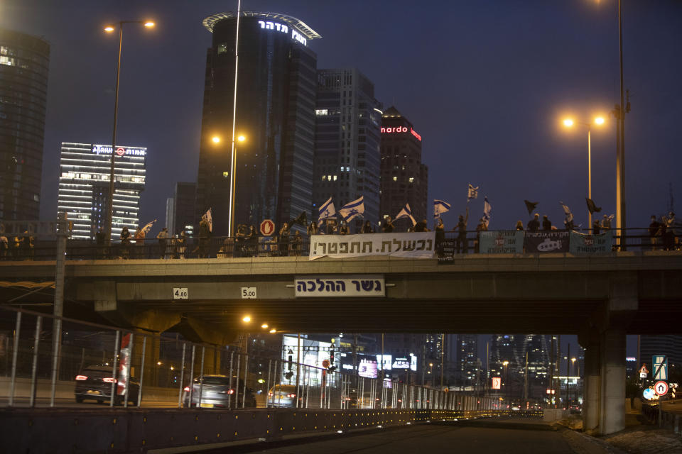 Israeli protesters hold flags and signs as they stand on a bridge to demonstrate against Israel's Prime Minister Benjamin Netanyahu in Tel Aviv, Israel, Saturday, Aug. 8, 2020. Hebrew reads: "You failed. resign!" (AP Photo/Sebastian Scheiner)