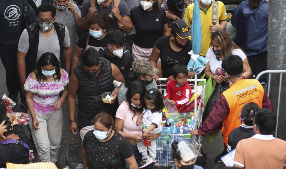 Pedestrians wearing face masks amid the COVID-19 pandemic walk in the Mesa Redonda Market, a popular spot for Christmas shopping in Lima, Peru, Friday, Dec. 18, 2020. Peru's Health Ministry has announced on Tuesday, Dec. 22, that it has surpassed 1 million confirmed cases of the new coronavirus. (AP Photo/Martin Mejia, File)