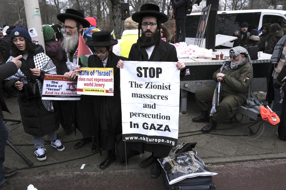 Protestors hold signs during a demonstration march outside the International Court of Justice in The Hague, Netherlands, Thursday, Jan. 11, 2024. The United Nations' top court opens hearings Thursday into South Africa's allegation that Israel's war with Hamas amounts to genocide against Palestinians, a claim that Israel strongly denies. (AP Photo/Patrick Post)