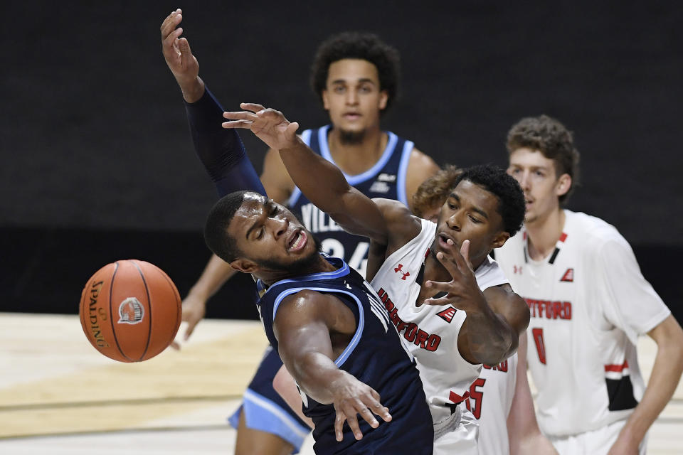 Villanova's Eric Dixon, left, and Hartford's Moses Flowers reach for a loose ball in the first half of an NCAA college basketball game, Tuesday, Dec. 1, 2020, in Uncasville, Conn. (AP Photo/Jessica Hill)