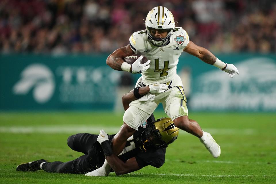 Gasparilla Bowl: Georgia Tech Yellow Jackets running back Dontae Smith (4) tries scramble out of the grasp of Central Florida Knights defensive back Decorian Patterson (11) during the game at Raymond James Stadium in Tampa.