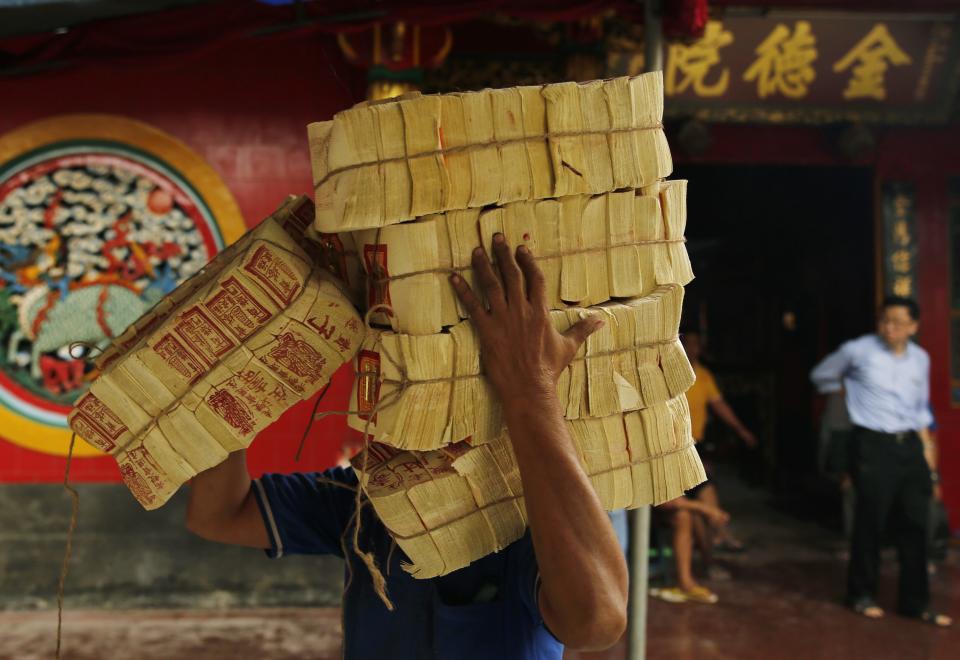 A worker carries offering papers before upcoming Chinese Lunar New Year celebrations, at Petak Sembilan temple in Jakarta