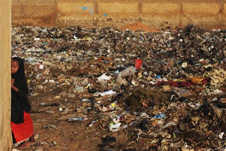 Six-year-old Hauwaou peers out from behind a wall next to a garbage dump in Niamey, September 15, 2013. REUTERS/Joe Penney