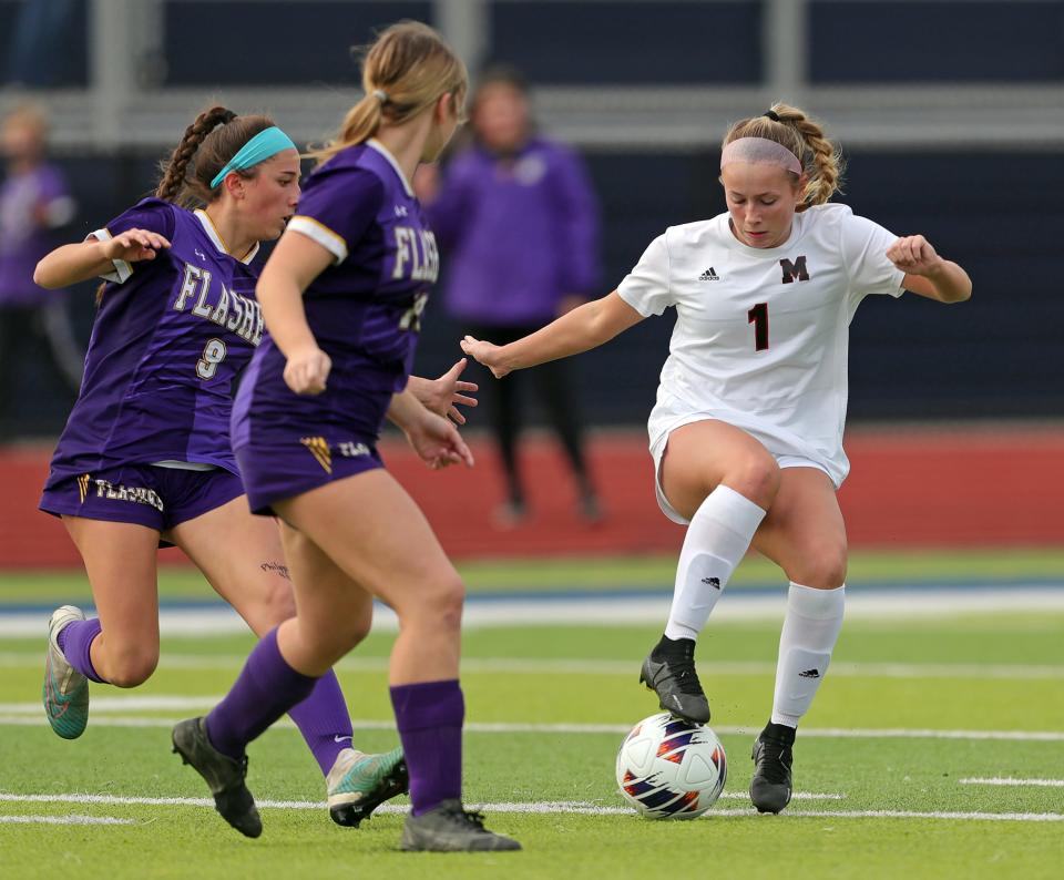 Manchester's Katie Norris, right, handles the ball against two Champion players during a regional final Saturday in Tallmadge.