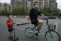 A man pulls a child along as they wear masks to curb the spread of the new coronavirus on the streets of Beijing, Saturday, May 30, 2020. (AP Photo/Ng Han Guan)