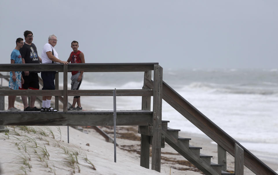 Beach goers watch waves churned up by Tropical Storm Isaias near Jaycee Beach Park, Sunday, Aug. 2, 2020, in Vero Beach, Fla. Isaias weakened from a hurricane to a tropical storm late Saturday afternoon, but was still expected to bring heavy rain and flooding as it barrels toward Florida. (AP Photo/Wilfredo Lee)