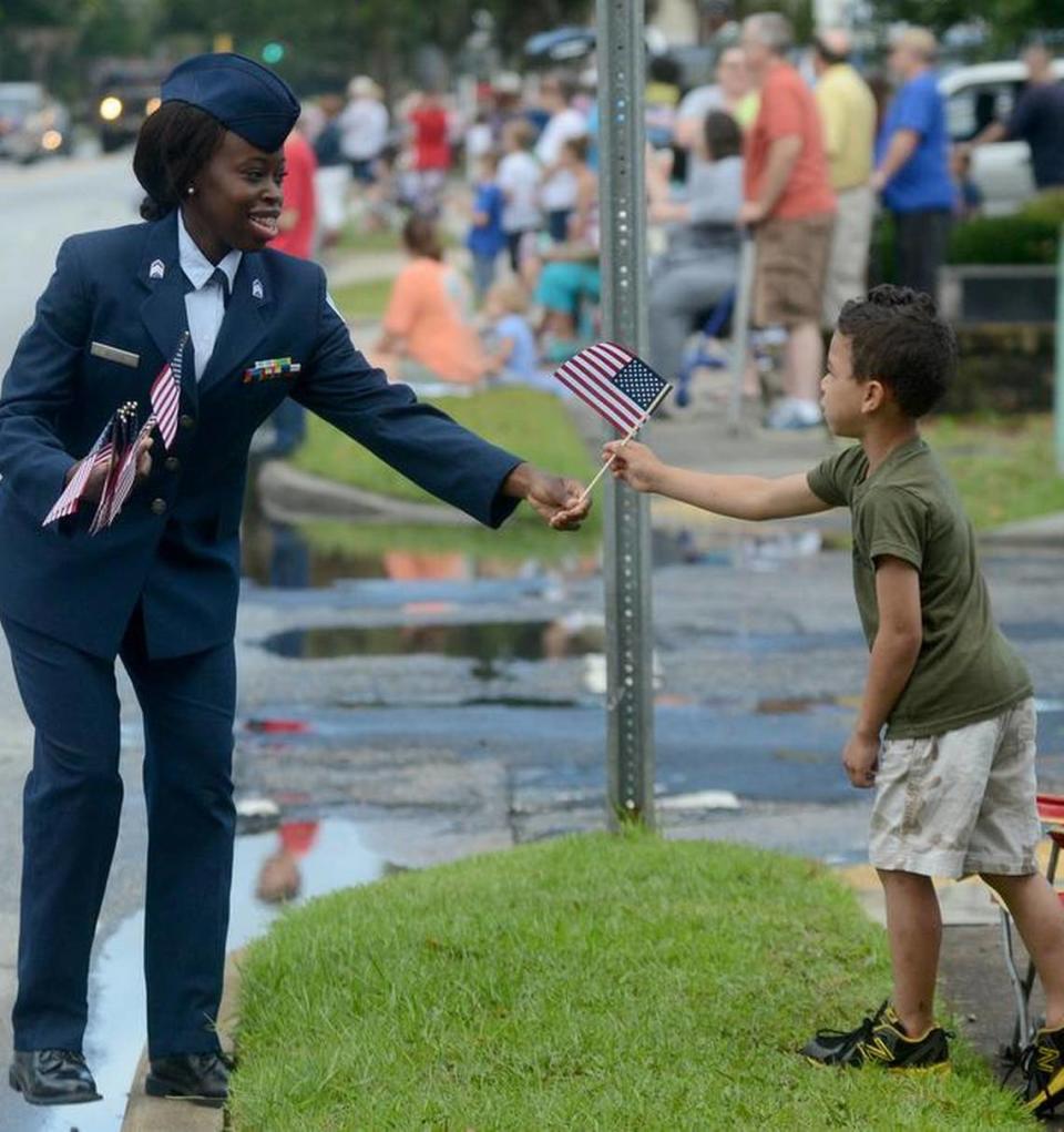 A woman walking with the American Legion float gives an American flag to a child during the Memorial Day Parade along Boundary Street on Monday, May 30, 2016, in Beaufort.