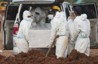 Workers in protective gear carry a coffin of a COVID-19 victim for burial at the special section of the Pedurenan cemetery in Bekasi, West Java, Indonesia, Friday, July 30, 2021. Indonesia surpassed the grim milestone of 100,000 official COVID-19 deaths on Wednesday, Aug. 4, 2021, as the country struggles with its worst pandemic year fueled by the delta variant, with growing concerns that the actual figure could be much higher with people also dying at home. (AP Photo/Achmad Ibrahim)