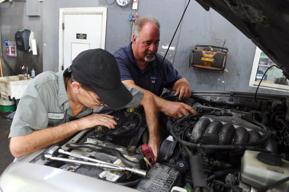 Bobby Ford (right) looks under the hood of a vehicle with longtime employee Greg Snead on Wednesday, Sept. 1, 2021, at Ford's automotive shop, Bobby's Auto Service Center, in Vero Beach. Several employees at the shop became infected with COVID-19, including Ford, who was vaccinated, and his twin brother, Billy Ford, who was not vaccinated. Eventually, Billy Ford had to be admitted to the hospital, sedated and put on a ventilator. Billy Ford died Aug. 14, leaving behind a wife, three children, his mother and three brothers.