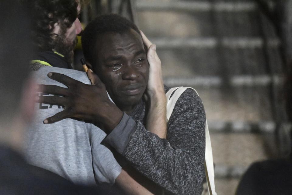 In this photo taken on Tuesday, Aug. 20, 2019 a man cries as he hugs a crew member after disembarking from the Open Arms rescue ship on the Sicilian island of Lampedusa, southern Italy. An Italian prosecutor ordered the seizure of a rescue ship and the immediate evacuation of more than 80 migrants still aboard, capping a drama Tuesday that saw 15 people jump overboard in a desperate bid to escape deteriorating conditions on the vessel and Spain dispatch a naval ship to try to resolve the crisis. (AP Photo/Salvatore Cavalli)