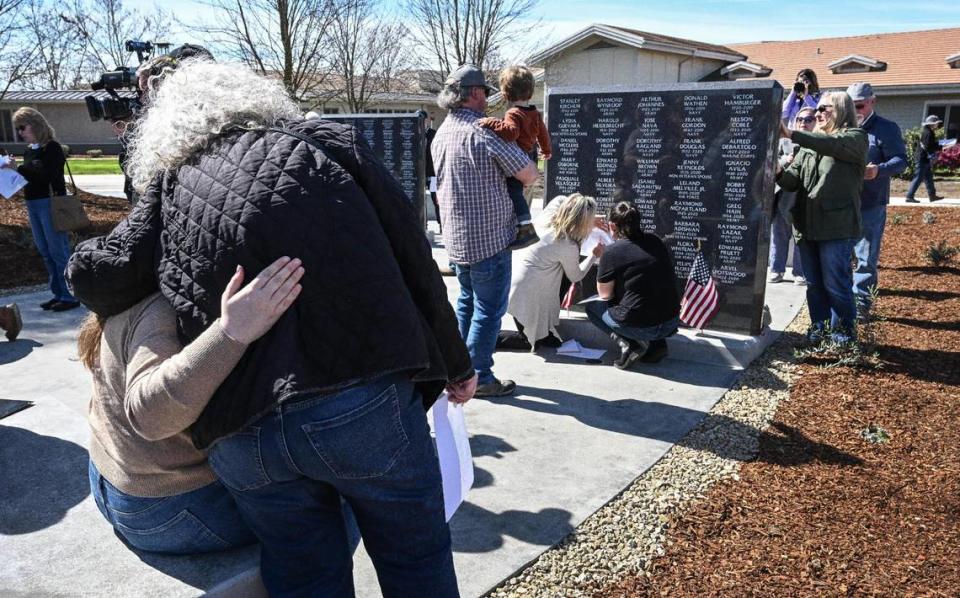Family members embrace as others seek out their loved ones names and do pencil rubbings during the unveiling of the Fresno Veterans Home Memorial Project to to honor those who called the facility their home at the Veterans Home of California in west Fresno on Monday, March 4, 2024.