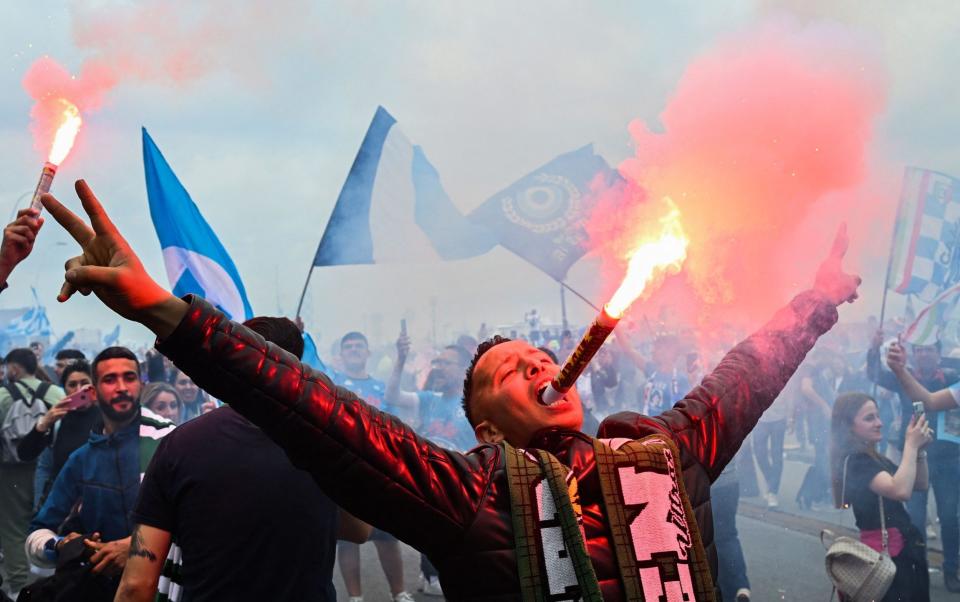  A fan of Napoli holds a flare bomb in his mouth as fans start to celebrate on the seafront of Naples - AFP/ALBERTO PIZZOLI