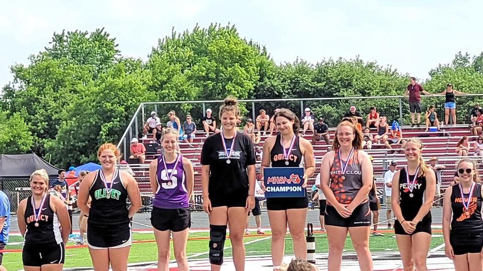Quincy's Sophia Snellenberger (center with sign-State Champion) and teammate Raigen Horsfall (far left-8th place) both earned All State honors in the discus at the D3 state finals on Saturday
