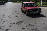 A taxi drives down a road damaged by shrapnel from a May rocket attack in Sloviansk, Donetsk region, eastern Ukraine, Saturday, Aug. 6, 2022. The echo of artillery shells thundering in the distance mingles with the din of people gathered around Sloviansk's public water pumps, piercing the uneasy quiet that smothers the nearly deserted streets of this eastern Ukrainian city. (AP Photo/David Goldman)