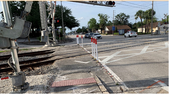An example of poles or delineators to block motorists from going around trains.