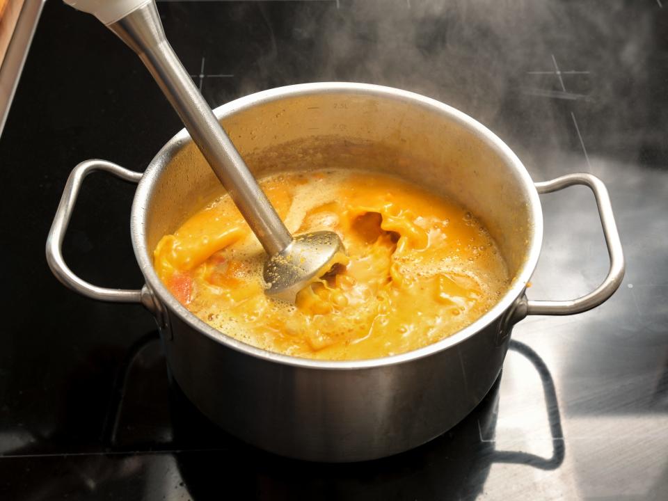 An immersion blender in a squash soup