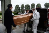 Varias personas sacan de un vehículo el ataúd de un fallecido para celebrar el funeral en Grassobbio. Todos ellos mantienen la distancia de seguridad y llevan mascarilla. (PIERO CRUCIATTI/AFP via Getty Images)