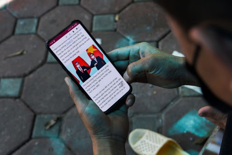 A man reads the news about Chinese foreign minister Wang Yi's visit to Vietnam, at a street in Hanoi