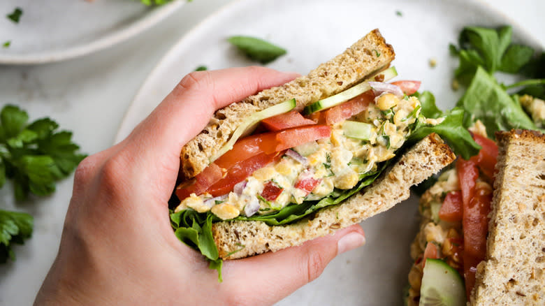 hand holding chickpea salad sandwich