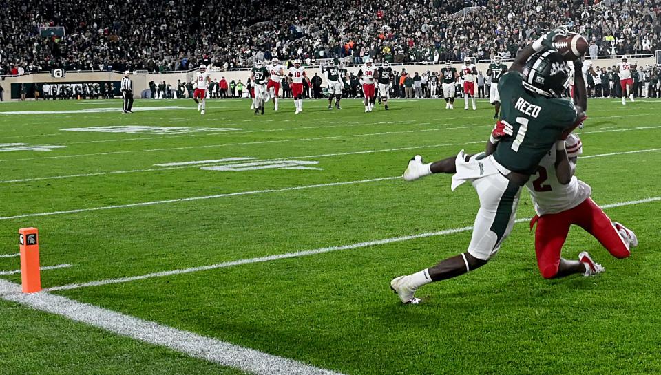 Michigan State Spartans wide receiver Jayden Reed (1) catches a touchdown pass with Wisconsin Badgers cornerback Ricardo Hallman (2) defending in a second overtime period to win the game, 34-28, on Saturday, Oct. 15, 2022, at Spartan Stadium.