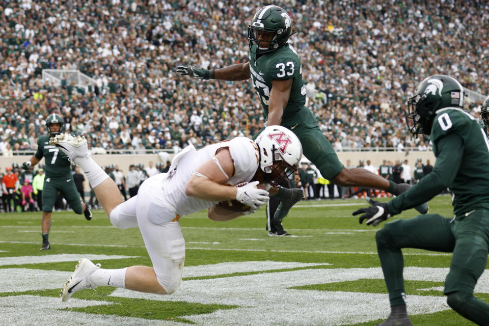 Minnesota tight end Nick Kallerup, left, catches a pass for a touchdown against Michigan State's Kendell Brooks (33) and Charles Brantley, right, during the second half of an NCAA college football game, Saturday, Sept. 24, 2022, in East Lansing, Mich. Minnesota won 34-7. (AP Photo/Al Goldis)