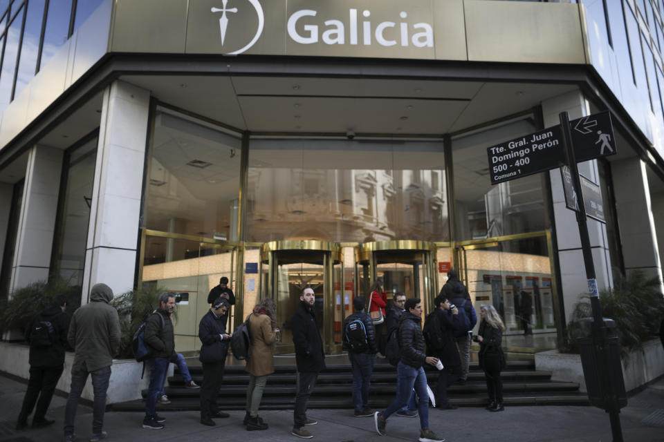 People wait for a bank to open in Buenos Aires, Argentina, Monday, Sept. 2, 2019. Argentina's government decreed on Sunday that Argentines will need authorization from the central bank to buy U.S. dollars in some cases and make transfers abroad for the rest of the year as it tries to prop up its peso currency. (AP Photo/Natacha Pisarenko)