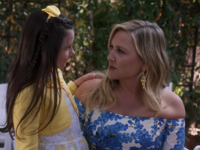 Arizona wearing a white and blue dress and talking to a young girl outside on Greys Anatomy