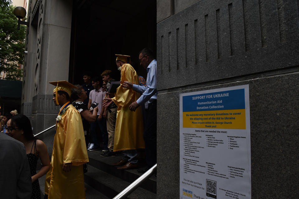 Graduates pose for pictures by posters that say how to donate to Ukraine