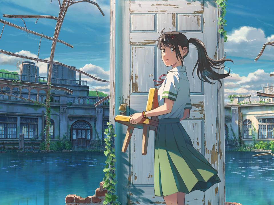 suzume in the anime film suzume — she's a teenage girl with her hair pulled back in a ponytail and with a red clip holding back her bangs, dressed in a school uniform with a green skirt, white shirt, and red ribbon around her neck. she's standing in the center of a shallow pool, the remnants of a bath house, in front of a weathered door. in her hands, she's holding a three-legged children's chair