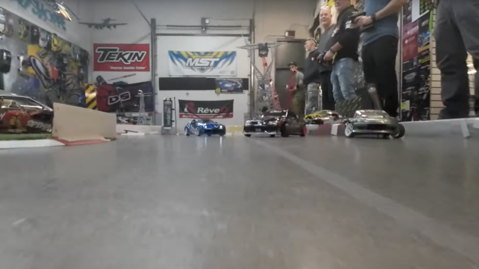 a group of people driving rc cars on track with camera car