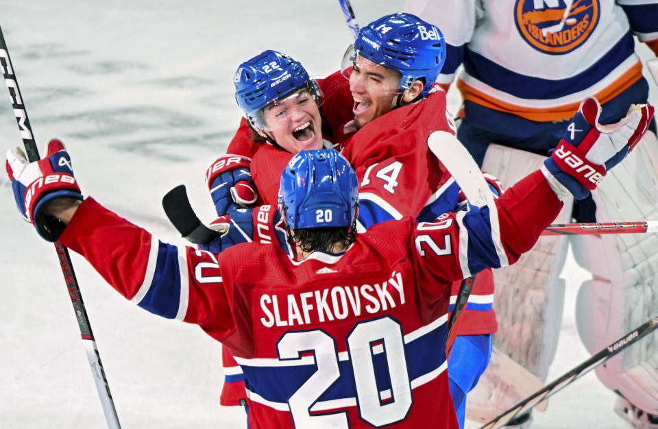 Montreal Canadiens' Cole Caufield (22) celebrates with teammates Nick Suzuki (14) and Juraj Slafkovsky (20) after scoring against the New York Islanders during the second period of an NHL hockey match in Montreal, Saturday, Dec. 16, 2023. (Graham Hughes/The Canadian Press via AP)