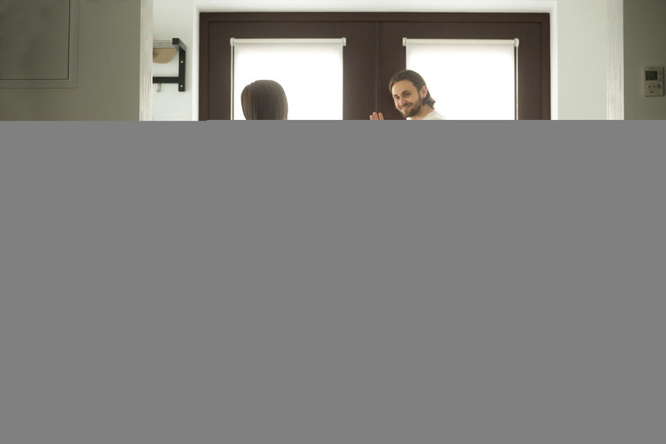 father leaving home waving to wife and daughter