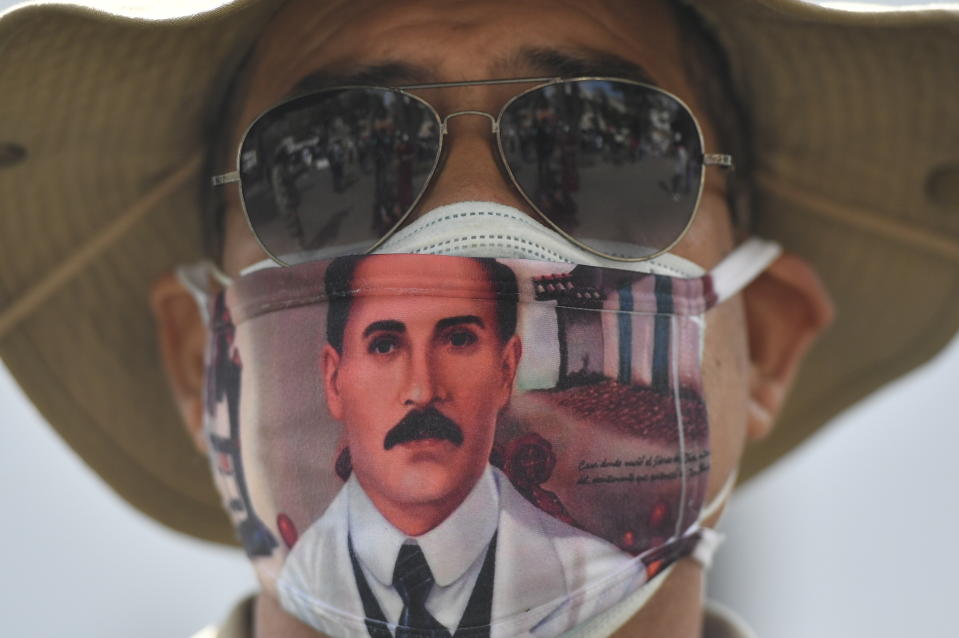 A man wears a mask featuring the image of the late, Venezuelan Dr. Jose Gregorio Hernandez, on the day of his Beatification ceremony outside the church that guards his remains in La Candelaria area of Caracas, Venezuela, Friday, April 30, 2021. Known as the "doctor of the poor, Hernandez will be beatified Friday by the Catholic church, a step towards sainthood. (AP Photo/Matias Delacroix)