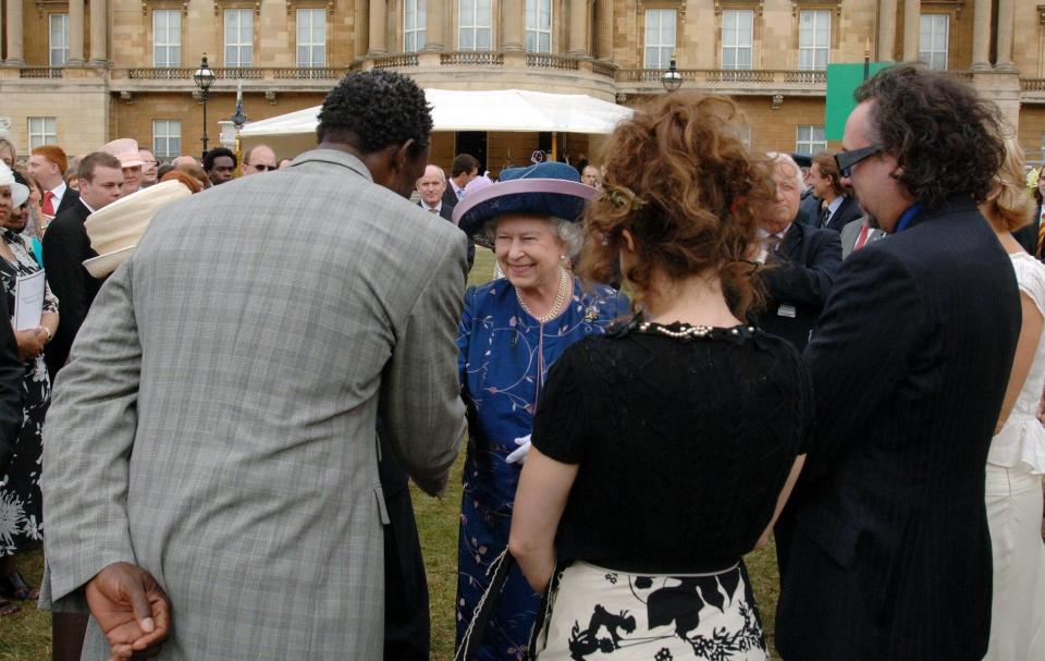 Queen Elizabeth II meets guests (left to right) Linford Christie, Helena Bonham Carter and Tim Burton at a garden party to mark 50 years of the Duke of Edinburgh's award scheme at Buckingham Palace.   (Photo by Steve Parsons - PA Images/PA Images via Getty Images)