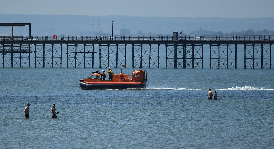 Members of the RNLI (Royal National Lifeboat Institution) patrol the water on a hovercraft as beachgoers enjoy the sunshine on the beach and in the sea on the May Bank holiday, in Southend-on-Sea, south east England on May 25, 2020, after lockdown restrictions, originally put in place due the COVID-19 pandemic, were lifted earlier this month. - British Prime Minister Boris Johnson on Sunday backed top aide Dominic Cummings despite mounting pressure from within his own party to sack him over claims he broke coronavirus lockdown regulations. (Photo by Ben STANSALL / AFP) (Photo by BEN STANSALL/AFP via Getty Images)