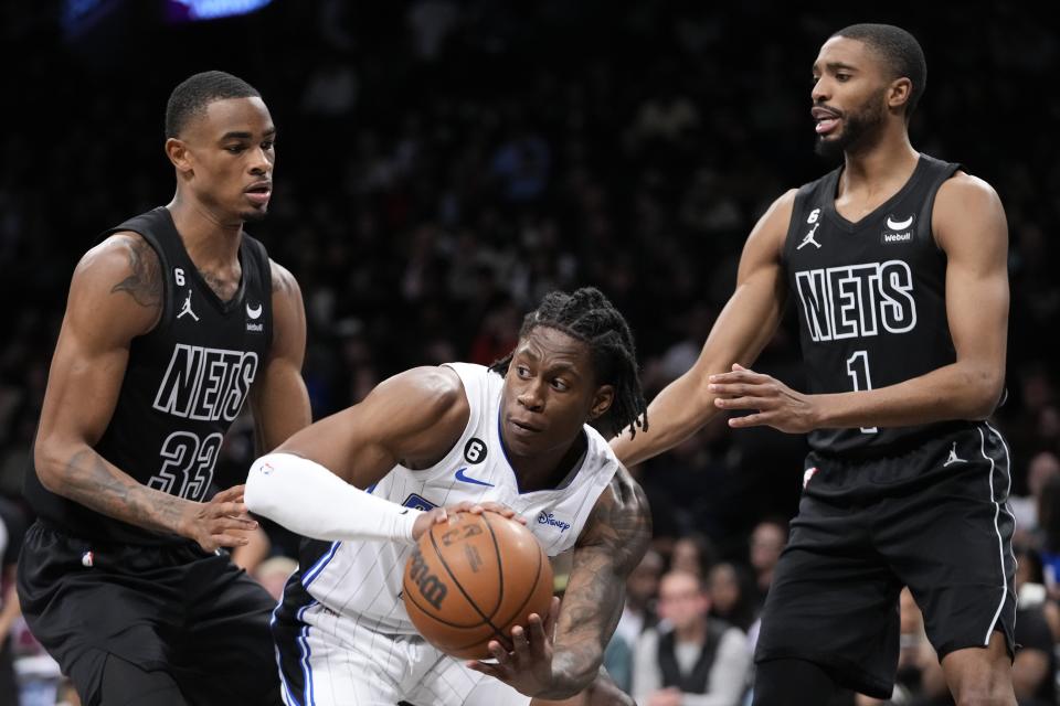 Orlando Magic forward Admiral Schofield, center, is defended by Brooklyn Nets center Nic Claxton (33) and forward Mikal Bridges (1) during the first half of an NBA basketball game Friday, April 7, 2023, in New York. (AP Photo/Mary Altaffer)