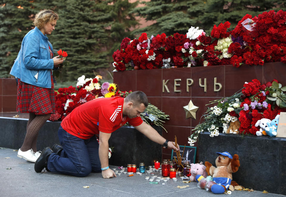 People bring flowers and candles to honor the victims of Wednesday's attack on a vocational college in Kerch, Crimea, in the Alexander Garden near the Kremlin, Moscow, Russia, Thursday, Oct. 18, 2018. A top official in Crimea says authorities are searching for a possible accomplice of the student whose shooting-and-bomb attack on his vocational school killed 20 people and wounded more than 50 others. (AP Photo/Pavel Golovkin)