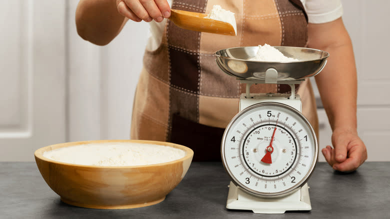 woman weighing flour on analog scales