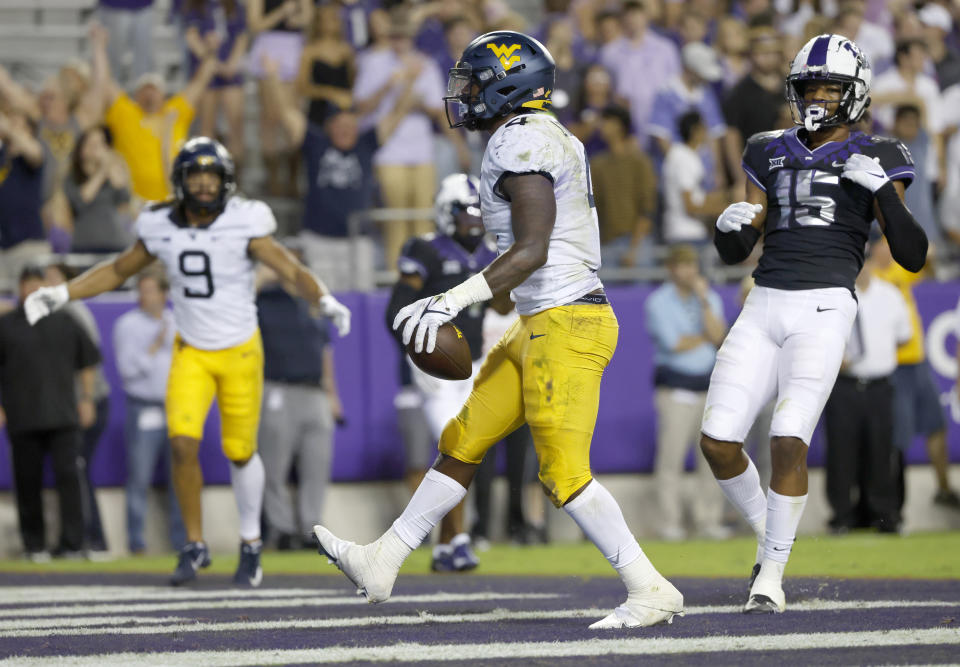 West Virginia running back Leddie Brown (4) reacts after running the ball into the end zone for a touchdown as TCU safety Josh Foster (15) looks on during the first half of an NCAA college football game Saturday, Oct. 23, 2021, in Fort Worth, Texas. (AP Photo/Ron Jenkins)