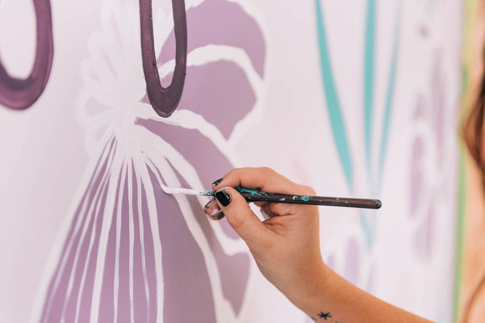 Woman Painting Wall Mural in Purple
