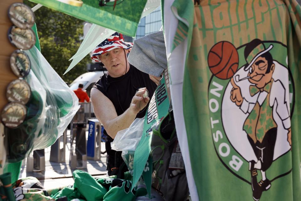 Rusty Dillenger, of Quincy, Mass., sells souvenirs in Copley Square before the Boston Celtics NBA basketball championship celebration parade Friday, June 21, 2024, in Boston. (AP Photo/Michael Dwyer)