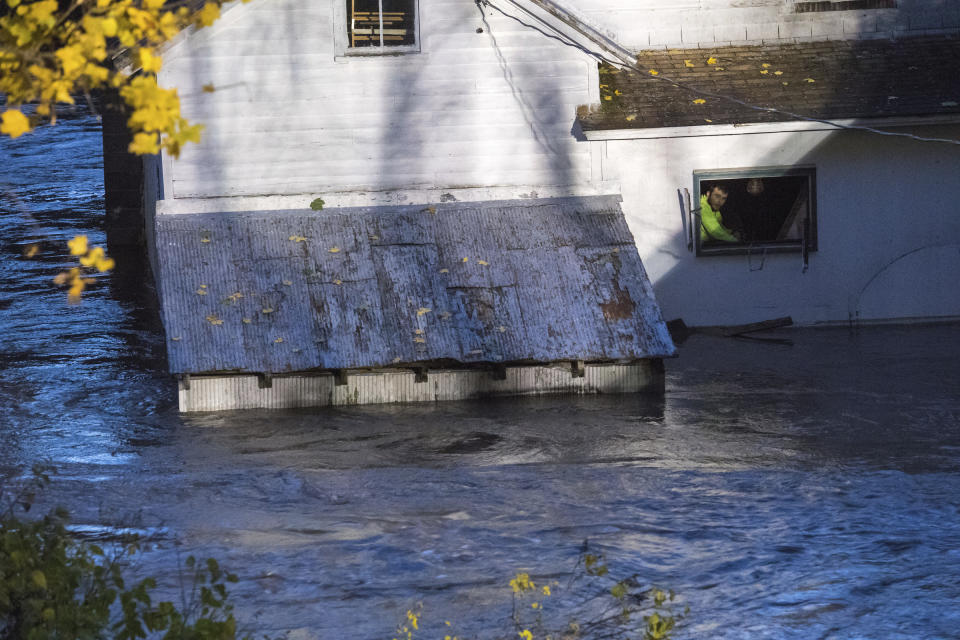 In this photo provided by the New York State Governor's Office, a man looks from a window of a house being flooded by rising waters of the East Canada Creek, Friday, Nov. 1, 2019 in Dolgeville, N.Y. He was rescued by local police. Several hundred people were being evacuated in scattered areas around the state because of high waters. (Darren McGee/New York State Governor's Office via AP)