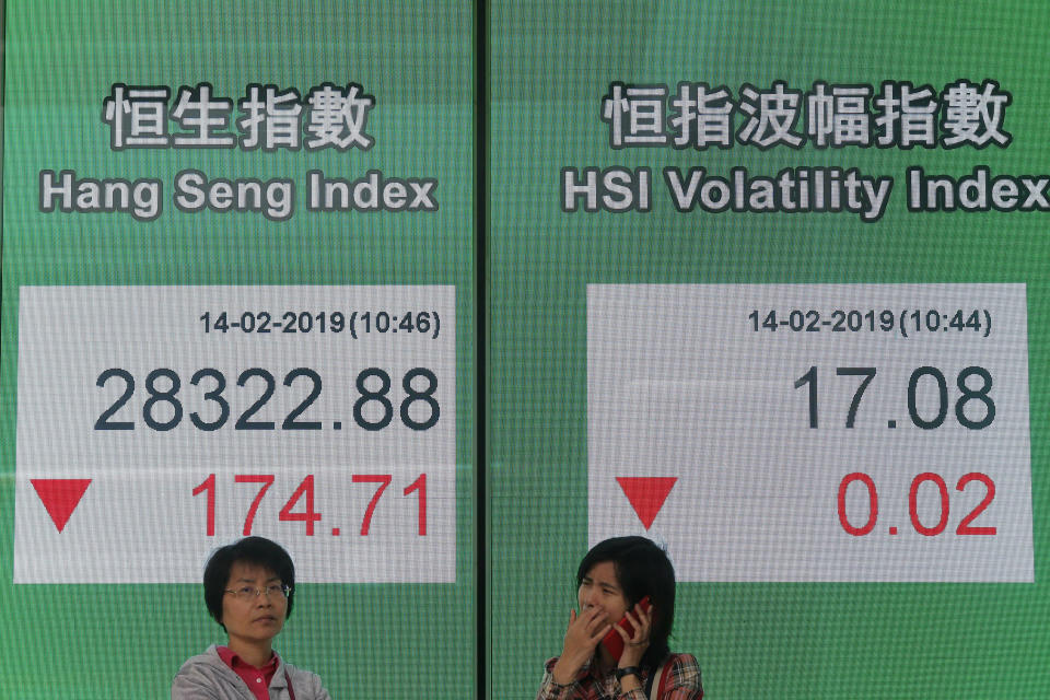 Two women stand in front of an electronic board showing Hong Kong share index outside a bank in Hong Kong, Thursday, Feb. 14, 2019. Asian stocks were mostly lower on Thursday as China and the U.S. kicked off two days of trade negotiations in Beijing. (AP Photo/Kin Cheung)